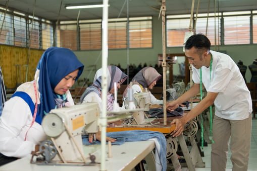 male tailor supervisor checks the work of the tailors in the garment convection production room