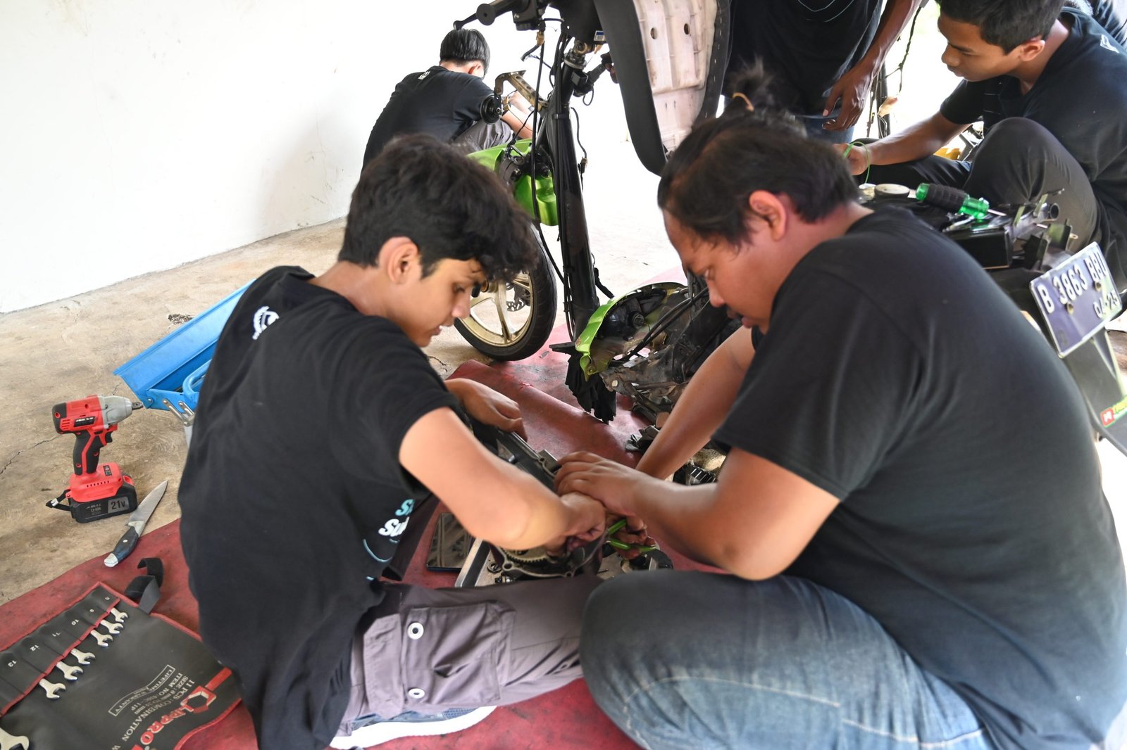Para peserta melakukan praktek langsung service motor matic dalam pelatihan pada Senin (04/11/2024).